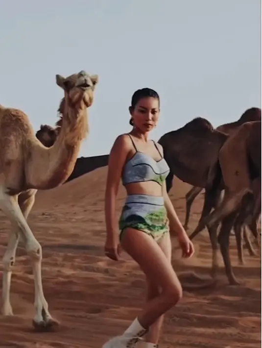 Berlatar padang pasir, Patricia Gouw berfoto bersama gerombolan unta yang kebetulan lewat [@patriciagouw]