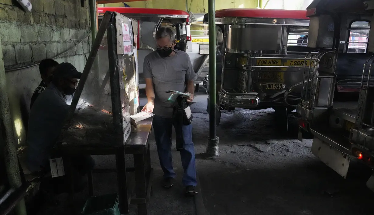 Seorang pria menunjukkan kartu vaksinasinya sebelum mengendarai jip penumpang di sebuah terminal di kota Quezon, Senin (17/1/2022). Pemerintah Filipina melarang orang yang belum menerima vaksin COVID-19 untuk naik transportasi umum di wilayah ibu kota Manila mulai Senin ini. (AP Photo/Aaron Favila)