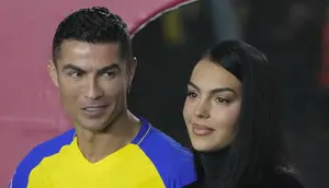 Cristiano Ronaldo menatap sang kekasih Georgina Rodriguez saat mereka menghadiri upacara penyambutan dirinya sebagai pemain baru Al Nassr di Stadion Mrsool Park, di ibu kota Saudi, Riyadh, Selasa (3/1/2023). Kekasih CR7 yang biasanya kerap memamerkan kemolekan tubuhnya terlihat lebih sopan dalam berpakaian. (AP Photo/Amr Nabil)