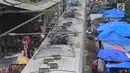 Suasana saat kereta commuter line melintas di rel KRL Nambo yang dipadati aktivitas jual beli pasar dadakan, Citeureup, Bogor (20/4). Meskipun berbahaya para pedagang tetap menjajakan dagangannya di tempat tersebut. (Merdeka.com/Arie Basuki)