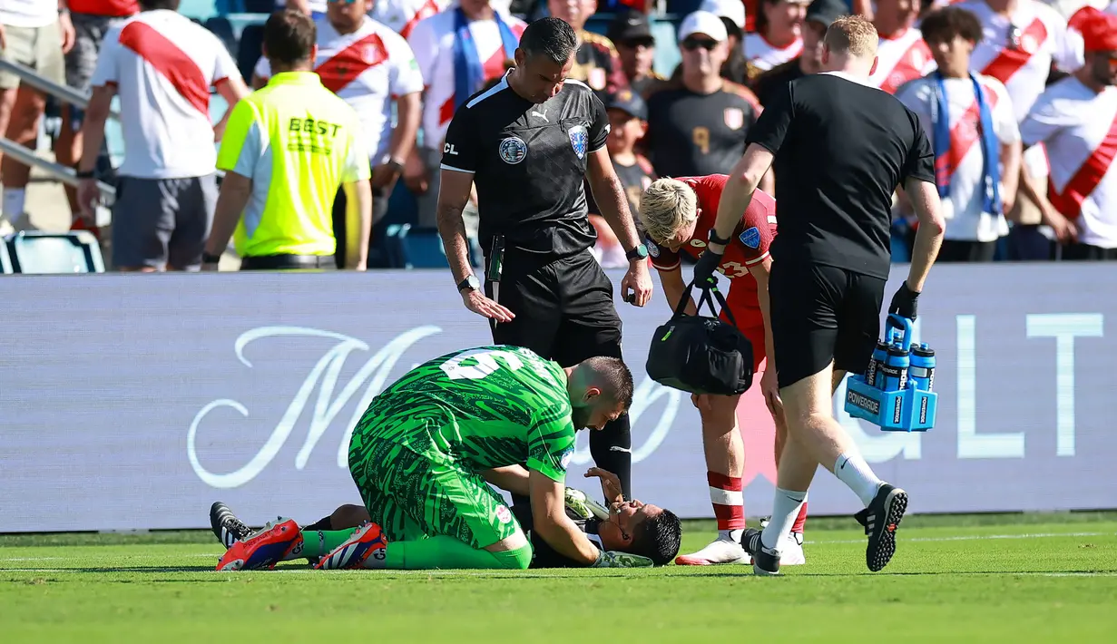 Kiper Kanada, Maxime Crepeau memberikan pertolongan kepada asisten wasit Humberto Panjoj saat mengalami pingsan pada laga Grup A Copa America 2024 antara Peru melawan Kanada di Children's Mercy Park, Kansas City, Kansas, Selasa (25/06/2024) waktu setempat. (AFP/Getty Images/Jamie Squire)