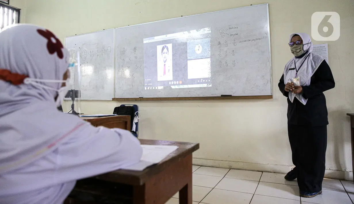 Guru memberikan materi pelajaran saat hari pertama uji coba pembelajaran tatap muka di SD Negeri 14 Pondok Labu, Jakarta, Senin (30/8/2021). Adapun seluruh pendidik dan tenaga kependidikan di sekolah yang menerapkan PTM Terbatas wajib telah divaksinasi COVID-19. (Liputan6.com/Faizal Fanani)