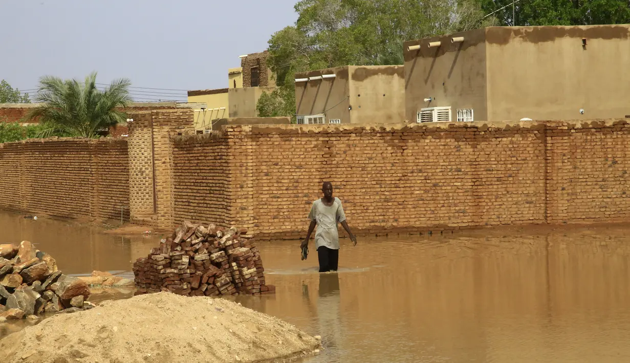 Seorang pria menyusuri jalanan yang tergenang banjir di Khartoum, Sudan (3/8/2020). Sudan dilanda banjir baru-baru ini akibat hujan lebat. (Xinhua/Mohamed Khidir)