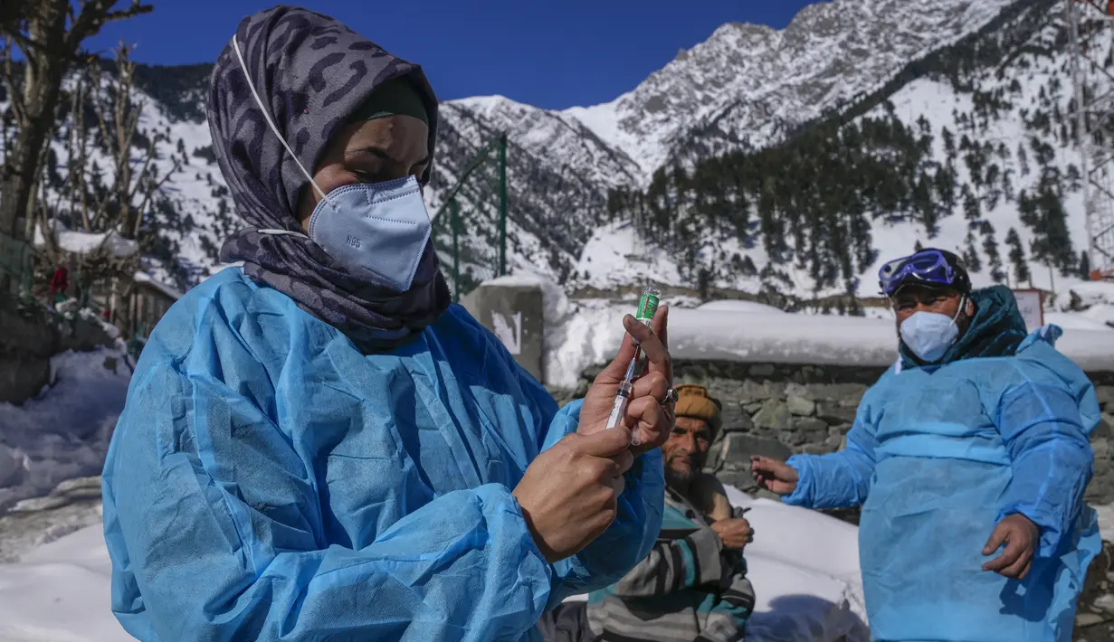 Masrat Farid, seorang petugas kesehatan, bersiap untuk memberikan dosis booster vaksin Covishield kepada Ghulam Hassan di jalan yang tertutup salju selama upaya vaksinasi COVID-19 di Gagangeer, timur laut Srinagar, Kashmir yang dikuasai India, pada 12 Januari 2022. (AP Photo/Dar Yasin)
