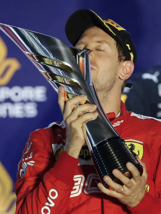 Pembalap Ferrari Sebastian Vettel berselebrasi di podium setelah memenangkan balapan Formula Satu (F1) Grand Prix Singapura di Sirkuit Jalan Marina Bay, Singapura (22/9/2019). Vettel berhasil menjuarai balapan dengan catatan waktu 1 jam:58menit:33.667 detik. (AP Photo/Vincent Thian)