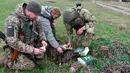 Tentara Ukraina memberi makan kucing dengan ransum kering Rusia di Pulau Ular, Laut Hitam, Ukraina, 18 Desember 2022. Pasukan Rusia menduduki pulau itu pada awal-awal invasinya ke Ukraina, namun akhirnya mundur beberapa bulan kemudian. (AP Photo/Michael Shtekel)