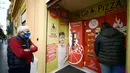 Seorang pria mengantre di mesin penjual pizza otomatis, yang pertama dari jenisnya di pusat kota Roma pada 29 April 2021. Mesin penjual otomatis ini mampu menguleni adonan, membumbui, memasak, dan menyajikan pizza dalam kotak karton hanya dalam waktu tiga menit. (Filippo MONTEFORTE/AFP)