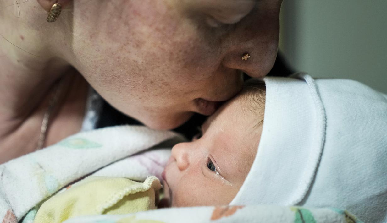 Kateryna Suharokova mencium putranya yang baru lahir, Makar di ruang bawah tanah rumah sakit bersalin yang diubah menjadi bangsal medis dan digunakan sebagai shelter bom di Mariupol, Ukraina, Senin (28/2/2022). Bayi itu lahir di tengah invasi militer Rusia ke Ukraina. (AP Photo/Evgeniy Maloletka)