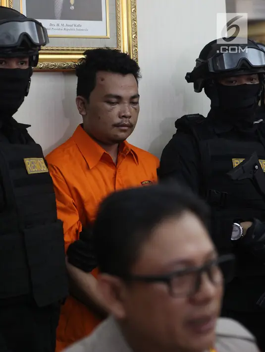 Polisi mengawal tersangka pembunuhan satu keluarga di Kota Bekasi saat gelar perkara di Polda Metro Jaya, Jakarta, Jumat (16/11). Tersangka dibekuk di Garut pada Rabu malam, 14 November 2018. (Merdeka.com/Imam Buhori)