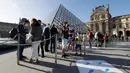 Pengunjung mengentre di piramida Louvre yang dirancang arsitek China Ieoh Ming Pei, pintu masuk ke Museum Louvre pada hari pertama pembukaan di Paris (6/7/2020). Setelah berbulan-bulan ditutup akibat lockdown Covid-19, Museum Louvre  kembali dibuka pada 6 Juli 2020. (AFP/Francois Guillot)