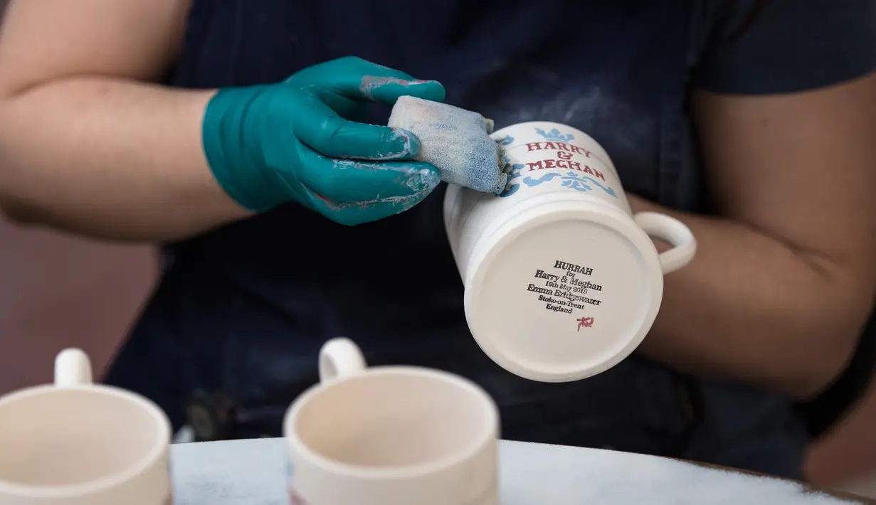 Seorang pekerja melukis dengan tangan mug untuk merayakan pernikahan Pangeran Harry dan Meghan Markle di pabrik Emma Bridgewater di Stoke-on-Trent, Inggris (16/4). Pangeran Harry dan Meghan Markle akan menikah pada 19 Mei 2018. (AFP/Oli Scarff)
