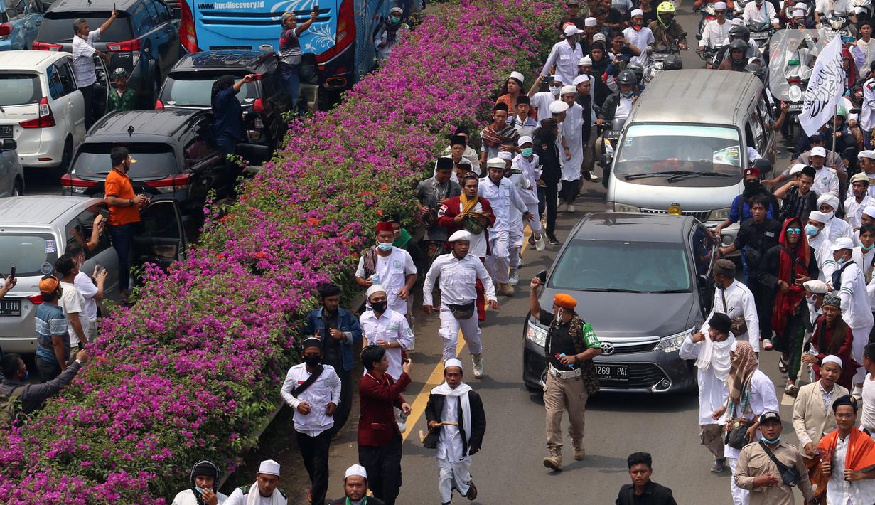 Ratusan massa berkonvoi mengawal Rizieq Shihab usai tiba di Bandara Soekarno-Hatta, Tangerang, Banten, Selasa (10/11/2020). Konvoi tersebut dilakukan untuk mengawal perjalan Rizieq Shihab menuju kediamannya di Petamburan, Jakarta. (Liputan6.com/Angga Yuniar)