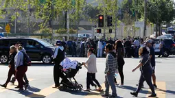 Para wali murid menunggu anak mereka di seberang lokasi penembakan di sekolah menengah Salvador Castro, Los Angeles, Kamis (1/2). Kepolisian mengatakan bahwa tersangka penembak dan senjata yang dimiliki sudah diamankan oleh polisi. (AP/Damian Dovarganes)
