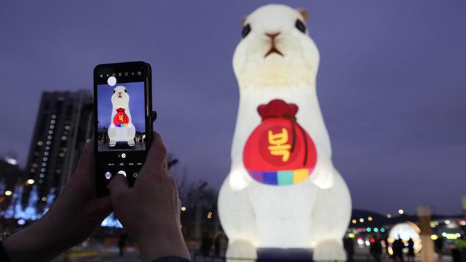 Seorang pengunjung mengambil foto lentera raksasa saat perayaan Tahun Kelinci 2023 mendatang di Lapangan Gwanghwamun, Seoul, Korea Selatan, Senin (19/12/2022). Festival Lentera ini akan berlangsung dari 19-31 Desember 2022. (AP Photo/Ahn Young-joon)