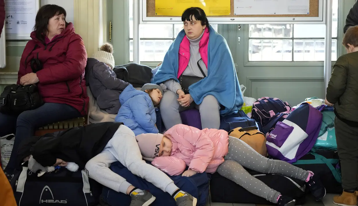 Anak-anak dari Ukraina tidur di stasiun kereta api di Przemysl, Polandia tenggara, pada Rabu (23/3/2022). Polandia telah menerima lebih dari 2 juta pengungsi Ukraina sejak invasi Rusia pada 24 Februari lalu. (AP Photo/Sergei Grits)