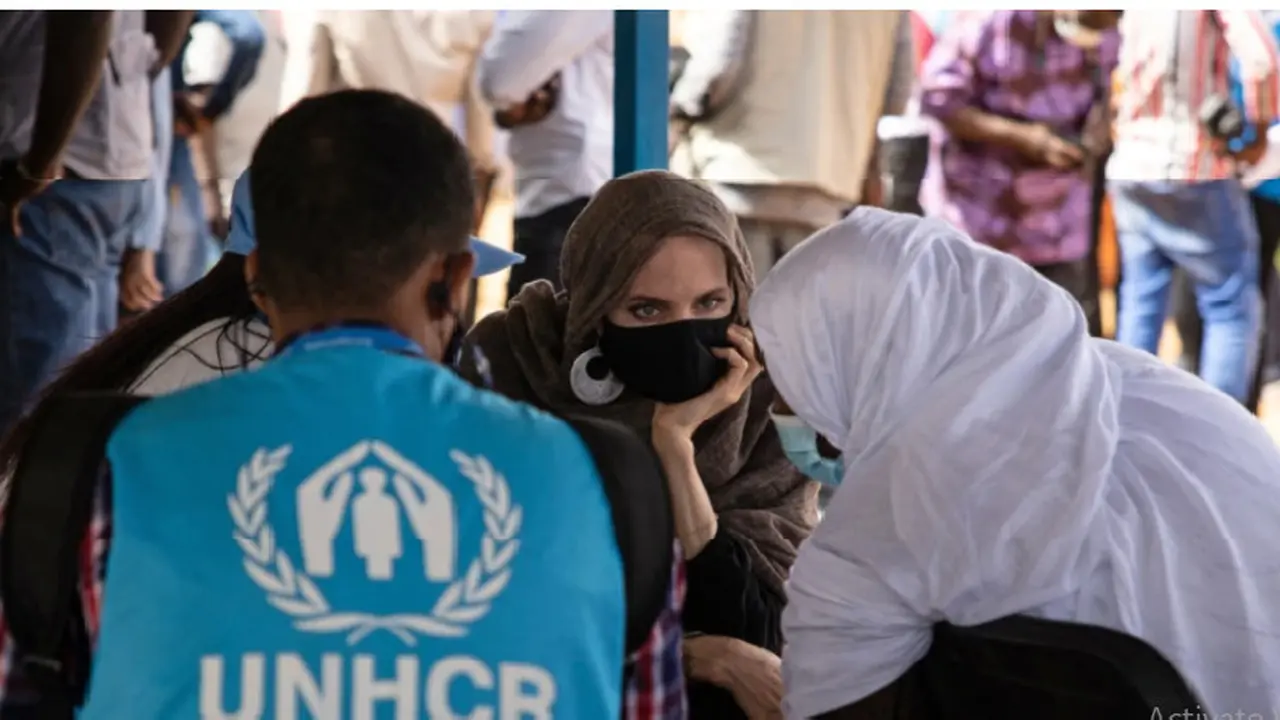 Aktris Angelina Jolie, utusan khusus badan PBB untuk urusan pengungsi (UNHCR), berbincang-bincang dengan Pengungsi Mali di Kamp Goudebo, di utara Burkina Faso, dalam peringatan Hari Pengungsi Sedunia, Minggu, 20 Juni 2021. (Olympia de Maismont/AFP)