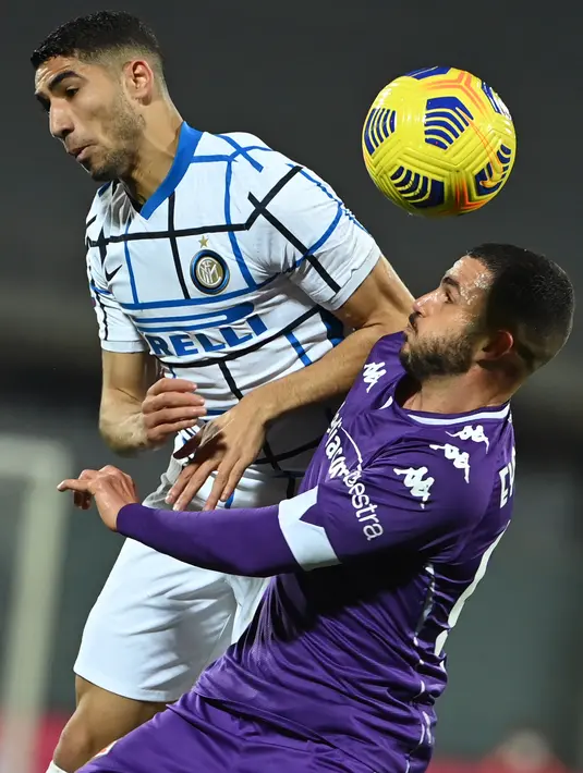Bek Inter Milan Achraf Hakimi dan gelandang Fiorentina Valentin Eysseric melakukan sundulan pada lanjutan laga Liga Italia di Stadion Artemio Franchi, Sabtu dinihari WIB (6/2/2021). Inter Milan mengalahkan Fiorentina 2-0 dan menggusur AC Milan dari puncak klasemen Serie A.  (Alberto PIZZOLI/AFP)