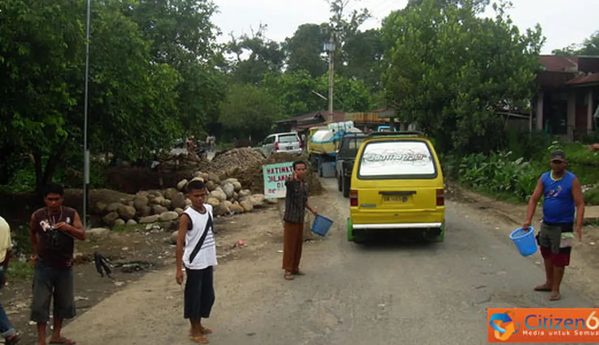 Citizen6, Tanah Karo: Jalan Raya Medan Tanah Karo di kilometer 24, 25 Desa Sugau, Pancur Batu, longsor. Kondisi ini dimanfaatkan sejumlah warga setempat turun mengatur lalu lintas, Sabtu (3/7). (Pengirim: Muhammad Ali)

