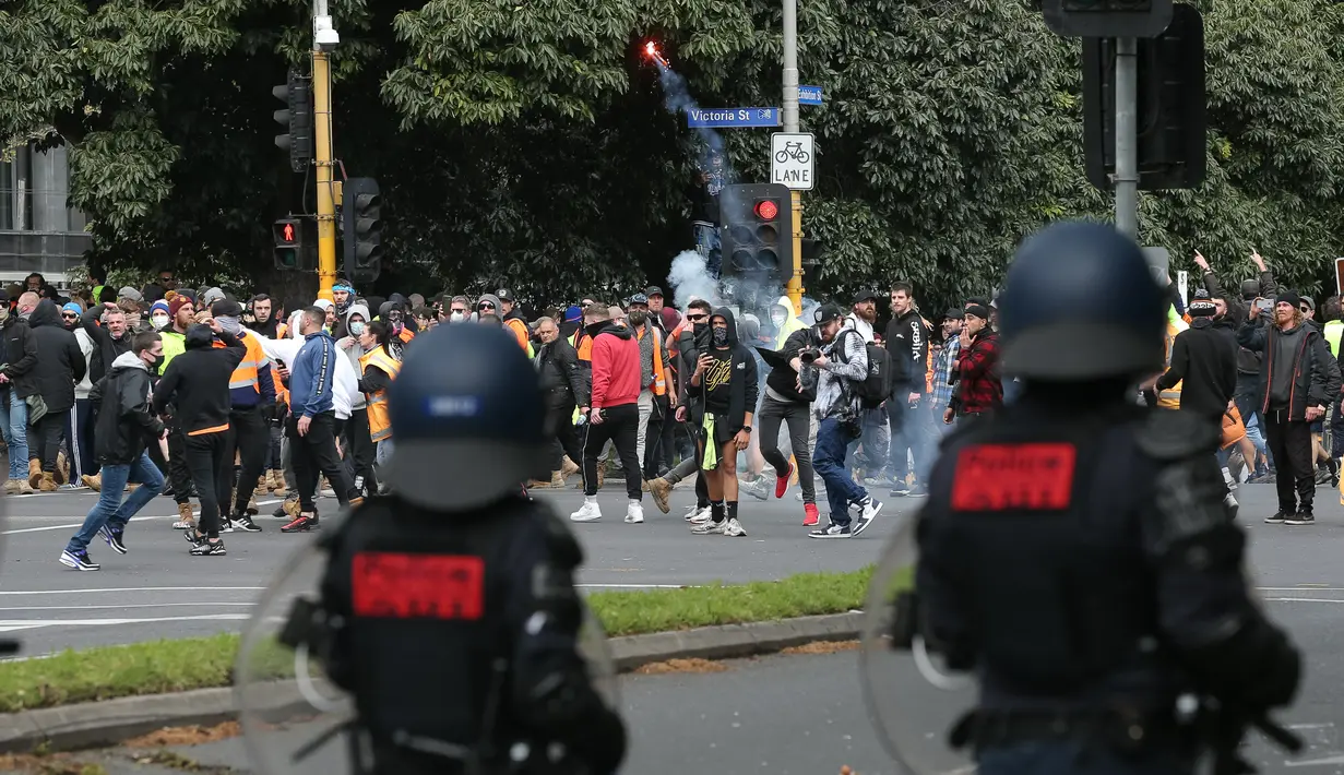 Seorang demonstran melemparkan suar saat protes terhadap peraturan Covid-19 di Melbourne (21/9/2021). Ribuan orang membuat kekacauan dan bentrok dengan polisi di kota dan mengambil alih jalan raya utama Melbourne saat protes terjadi. (AFP/STR)