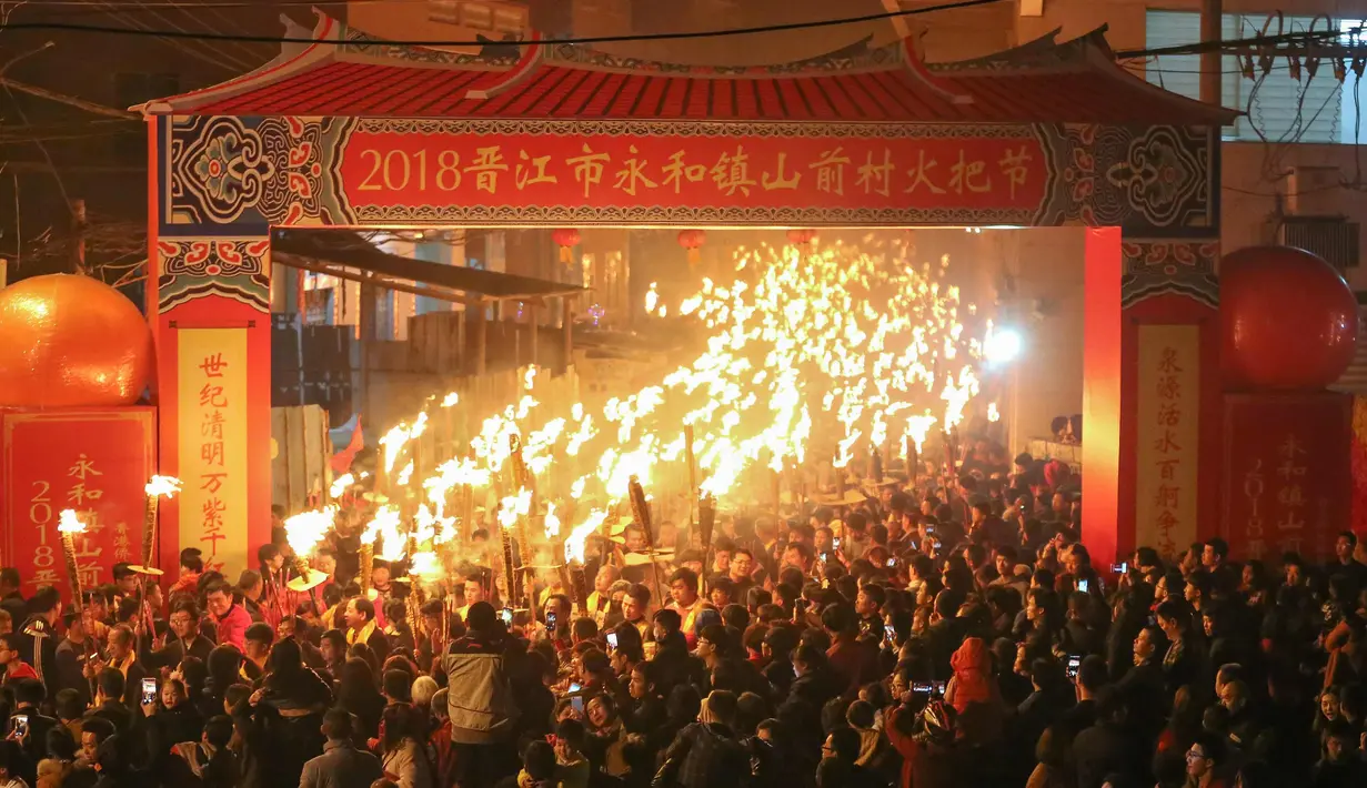 Ratusan warga memegang obor mengikuti parade untuk berdoa semoga berhasil di tahun baru saat sebuah festival obor di Jinjiang di provinsi Fujian, China timur (24/2). (AFP Photo)