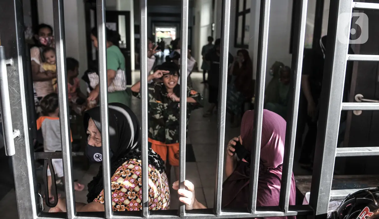 Aktivitas warga korban banjir di lorong kelas saat mengungsi di SDN 01 Kampung Melayu, Jakarta, Minggu (21/2/2021). Sudah 2 hari ratusan warga dari 4 RW di Kelurahan Kampung Melayu mengungsi di gedung sekolah lantaran banjir yang merendam rumah mereka tak kunjung surut. (merdeka.com/Iqbal S Nugroho)