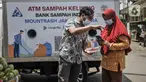 Petugas mendampingi warga saat memindai sampah botol melalui aplikasi smartphone sebelum ditabung ke ATM Sampah Keliling di kawasan Semper Barat, Cilincing, Jakarta Utara, Selasa (12/10/2021). (merdeka.com/Iqbal S. Nugroho)
