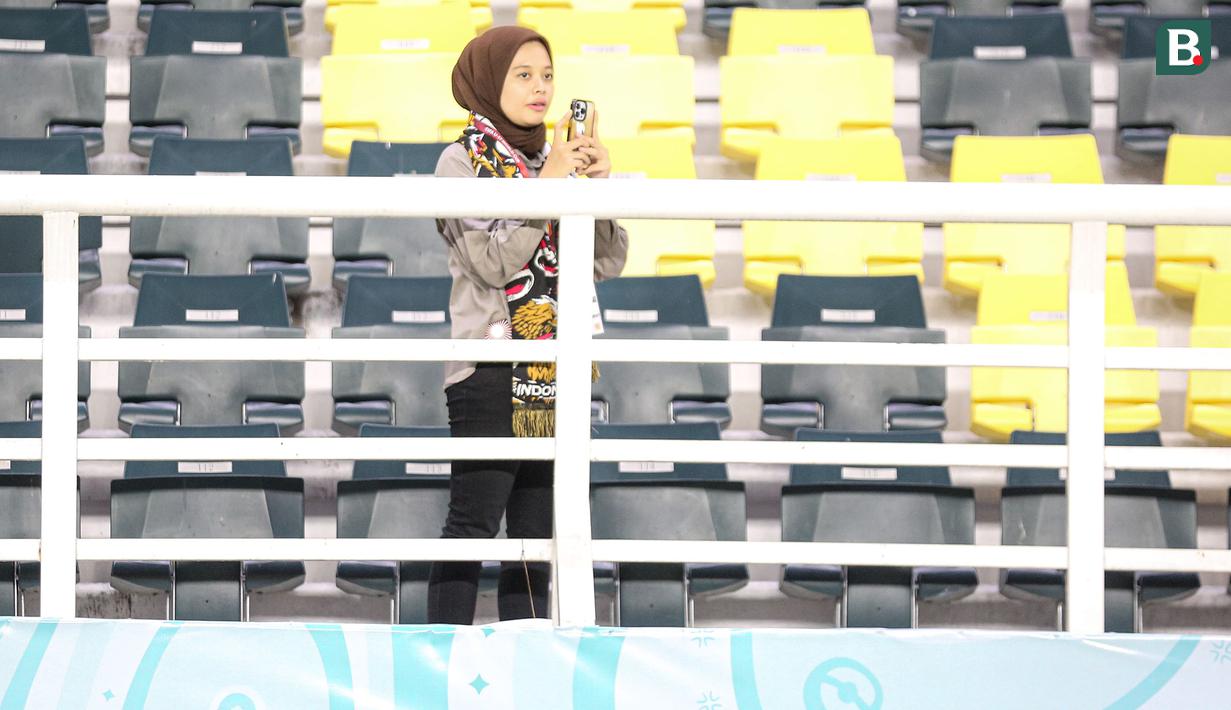 Seorang suporter wanita Indonesia menunggu momen-momen menarik Timnas Indonesia U-17 untuk diabadikan lewat gadgetnya saat menghadapi Timnas Panama U-17 pada laga kedua Grup A Piala Dunia U-17 2023 di Stadion Gelora Bung Tomo, Surabaya, Senin (13/11/2023). (Bola.com/Bagaskara Lazuardi)