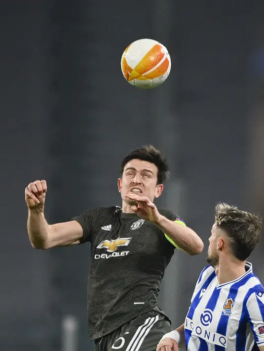 Bek Manchester United, Harry Maguire berebut bola dengan gelandang Real Sociedad, Adnan Januzaj pada leg pertama babak 32 besar Liga Europa di stadion Juventus, Turin (19/2/2021). Berkat hasil ini, MU lebih mudah melangkahkan satu kaki mereka di babak 16 besar. (Marco Alpozzi/LaPresse via AP)