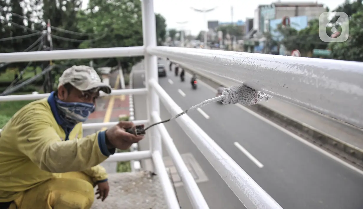 Petugas Sudin Bina Marga Jakarta Timur memperbaiki jembatan penyeberangan orang (JPO) di Jalan Otto Iskandardinata (Otista), Jatinegara, Rabu (9/2/2022). Perbaikan JPO itu tindak lanjut pasca insiden tertimpa pohon tumbang pada November tahun lalu akibat cuaca ekstrem. (merdeka.com/Iqbal S Nugroho)