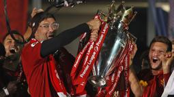 Pelatih Liverpool, Jurgen Klopp, mengangkat trofi juara Premier league 2019-2020 di Stadion Anfield, Kamis (23/7/2020) dini hari WIB. Prosesi angkat trofi juara ini dilakukan usai pertandingan Liverpool melawan Chelsea. (AFP/Phil Noble/pool)
