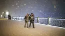 Pejalan kaki yang sebagian tertutup salju berjalan dekat jembatan Galata saat salju turun di Istanbul, Turki, Sabtu (12/3/2022). Salju tebal menutupi Istanbul dan mengganggu lalu lintas udara menyebabkan transportasi laut serta darat terhenti, hingga memaksa penutupan sekolah. (AP Photo/Emrah Gurel)
