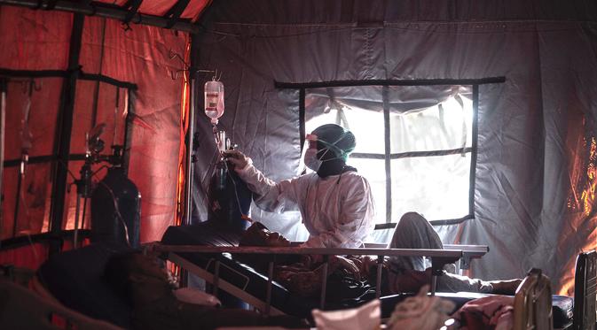 Tenaga medis merawat pasien Covid-19 di tenda yang didirikan di luar rumah sakit di Bogor pada 29 Juni 2021, saat infeksi melonjak di Indonesia. Provinsi yang cukup banyak mengalami kematian di luar RS adalah Jawa Barat sejumlah 97 kematian dari 11 kota/kabupaten. (AFP/ Aditya Aji)