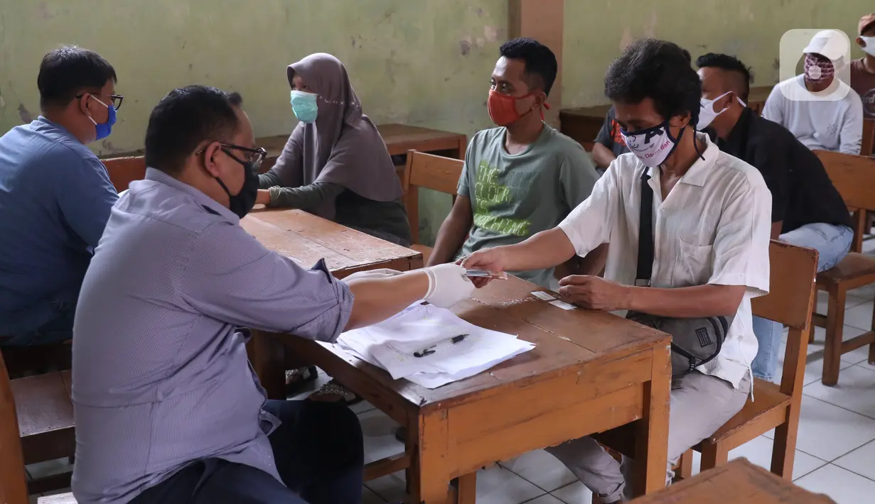 Petugas menyerahkan bantuan sosial (bansos) dari Pemerintah Provinsi Banten kepada warga di Pinang, Tangerang, Jumat (1/5/2020). Bansos berupa uang tunai sebesar Rp 600 ribu tersebut diberikan kepada warga yang terdampak virus corona COVID-19. (Liputan6.com/Angga Yuniar)