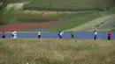 Wisatawan berjalan di tengah-tengah bunga yang sedang mekar dan ladang lentil di Castelluccio, sebuah desa kecil di wilayah Umbria, Italia tengah pada 6 Juli 2020. Setiap tahunnya antara Mei dan Juli, ribuan varietas bunga liar  bermekaran dan menjadi daya tarik wisatawan. (Tiziana FABI / AFP)