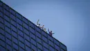 Pendaki Alain Robert (kanan) atau Spiderman Prancis bersama Marcin Banot, Alexis Landot, dan Leo Urban melakukan perayaan di puncak Menara Total usai memanjatnya di La Defense, Paris, Prancis, 7 September 2021. (THOMAS SAMSON/AFP)