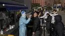 Orang-orang mengantre untuk mendapatkan tes COVID-19 di fasilitas pengujian virus corona seluler di luar gedung perkantoran komersial di Beijing (16/1/2022). Beijing telah melaporkan infeksi omicron lokal pertamanya, beberapa minggu sebelum Olimpiade Musim Dingin akan dimulai. (AP Photo/Andy Wong)