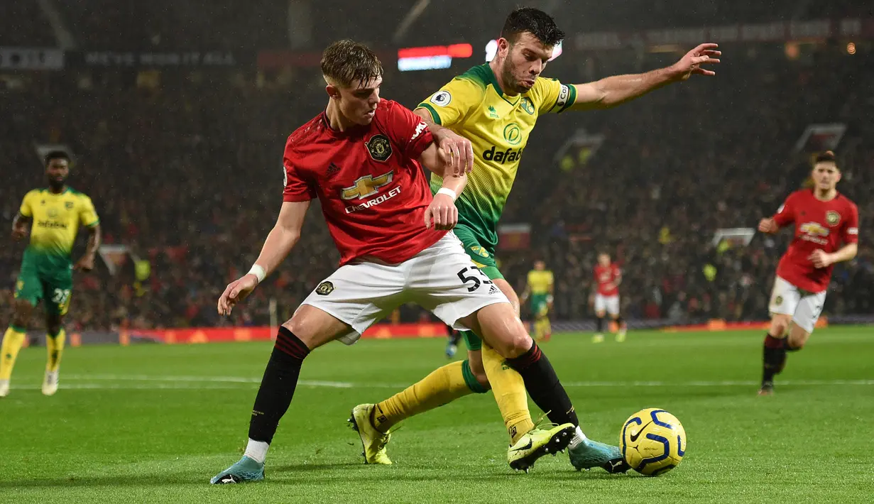 Bek Norwich City, Grant Hanley (kanan) berebut bola dengan bek Manchester United, Brandon Williams (kiri) selama pertandingan pertandingan lanjutan Liga Inggris di Old Trafford (11/1/2020). MU menang telak 4-0 atas Norwich. (AFP/Oli Scarff)