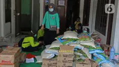Warga mengemas bantuan bahan pokok untuk pasien positif Covid-19 di RT03/RW03, Kelurahan Cilangkap, Jakarta, Jumat (21/5/2021). Sebanyak 25 paket bahan pokok dari bantuan Dinas Sosial DKI Jakarta dan swadaya warga setempat diberikan kepada 25 Kepala Keluarga. (Liputan6.com/Herman Zakharia)