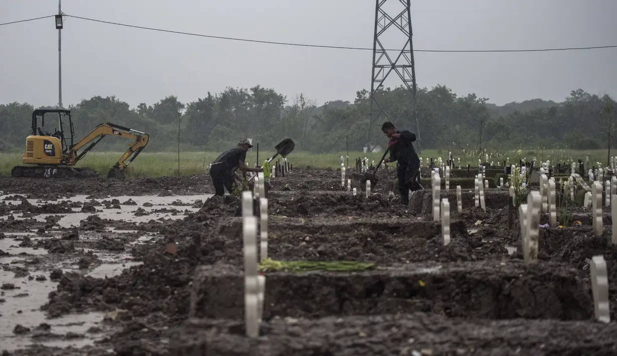 Penggali kubur menguburkan korban virus Corona Covid-19 di tengah guyuran hujan di pemakaman Keputih, Surabaya (7/1/2020). (AFP/Juni Kriswanto)
