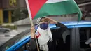 Seorang wanita Muslim memberi hormat dengan bendera Palestina saat konvoi protes menentang serangan Israel di Gaza di luar Kedutaan Besar Amerika Serikat di Kuala Lumpur, Malaysia, Jumat (21/5/2021).  (AP Photo / Vincent Thian)