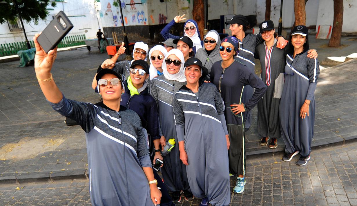 Perempuan Arab Saudi berswafoto saat jogging memperingati Women's Day atau Hari Perempuan Internasional di jalanan Distrik Al-Balad, Jeddah, Kamis (8/3). Sejak Mohammed bin Salman menjadi Putra Mahkota, dia memodernisasi negerinya. (Amer HILABI/AFP)
