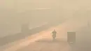 Pengendara melintas di sepanjang jalan di tengah kondisi kabut asap di Lahore, Pakistan (23/11/2021). Kondisi kabut asap yang memburuk membuat Lembaga pendidikan, kantor swasta tutup selama tiga hari seminggu di Lahore. (AFP/Arif Ali)