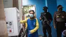 Polisi bersenjata bersiaga saat pekerja menurunkan vaksin COVID-19 produksi Sinovac dari truk setibanya di Surabaya pada Senin (4/1/2021).  Pemerintah mulai mendistribusikan 3 juta dosis vaksin Covid-19 asal perusahaan China, Sinovac, ke 34 provinsi Indonesia. (Photo by Juni Kriswanto / AFP)