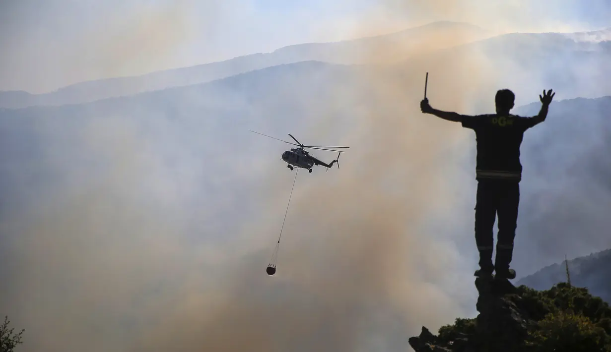 Sebuah helikopter berpartisipasi dalam operasi pemadaman kebakaran hutan di Koycegiz, Mugla, Turki, Senin (9/8/2021). Kebakaran hutan yang terjadi di tengah gelombang panas ganas telah berkobar selama berhari-hari di lebih dari setengah provinsi Turki. (AP Photo/Emre Tazegul)