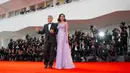 Pasangan selebritis, George dan Amal Clooney berpose untuk fotografer setibanya di Venice Film Festival ke-74, Italia, 2 September 2017. Di momen itu, Amal menebar pesonanya dalam balutan gaun sutra panjang koleksi Versace. (AP Photo/Domenico Stinellis)