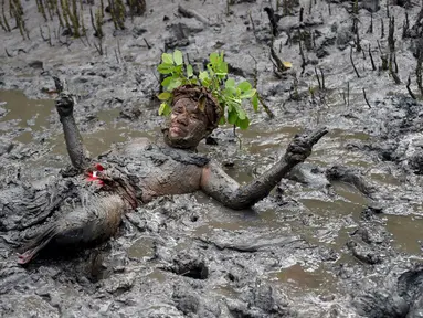 Seorang pria mengambil bagian dalam tradisi mandi lumpur yang dikenal sebagai Mebuug-buugan di Desa Kedonganan, Bali, 4 Maret 2022. Mebuug-buugan diadakan sehari setelah Nyepi yang bertujuan untuk menetralkan sifat buruk. (SONY TUMBELAKA/AFP)