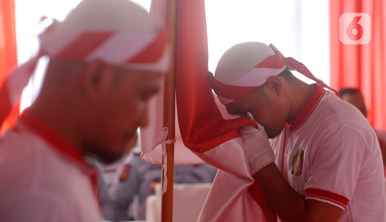 Warga binaan narapidana terorisme (napiter) mencium bendera Merah Outih saat melakukan ikrar dan janji setia Negara Kesatuan Republik Indonesia (NKRI) di Lapas Narkotika Kelas IIA, Gunung Sindur, Bogor, Jawa Barat, Kamis (1/6/2023). Sebanyak 76 warga binaan kasus terorisme melakukan ikrar dan janji setia NKRI sebagai salah satu wujud keberhasilan pembinaan dan mendorong kesadaran mereka untuk kembali dan mengakui Tanah Air Indonesia. (merdeka.com/Arie Basuki)
