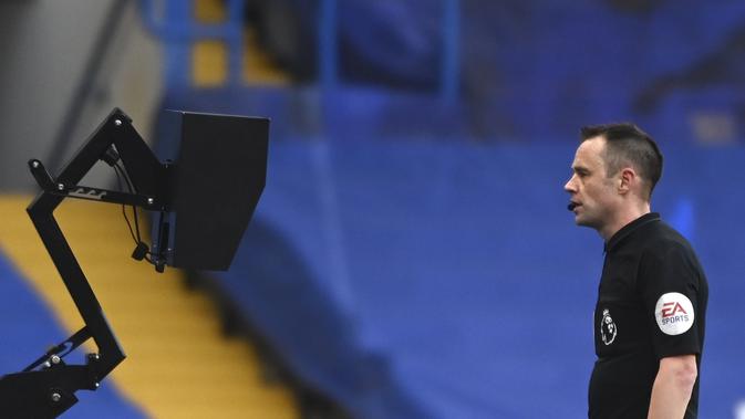 Wasit Stuart Attwell melihat VAR dalam laga Chelsea vs Manchester United atau MU dalam lanjutan Liga Inggris di Stamford Bridge, Minggu (28/2/2021). (Andy Rain/Pool via AP)