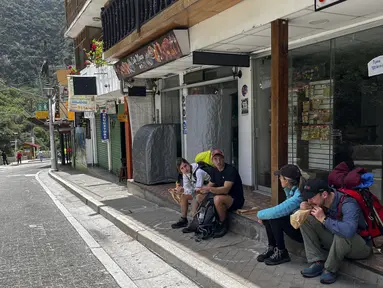 Turis menunggu di luar stasiun kereta Machu Picchu setelah layanan kereta api dihentikan karena kerusakan yang diduga disebabkan oleh pengunjuk rasa di Machu Picchu, Peru, Sabtu (21/1/2023). Demonstrasi besar di Peru yang menentang pemerintahan masih belum usai dan menyebabkan tempat wisata terkenal Machu Picchu ditutup. (Photo by Carolina Paucar / AFP)