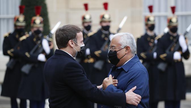 Presiden Prancis Emmanuel Macron (kiri) menyambut Perdana Menteri Portugis Antonio Costa di halaman Istana Elysee, sebelum makan siang kerja di Paris, Rabu (16/12/2020). Ini adalah kesekian kalinya pemimpin negara terinfeksi Covid-19. (AP Photo/Francois Mori)